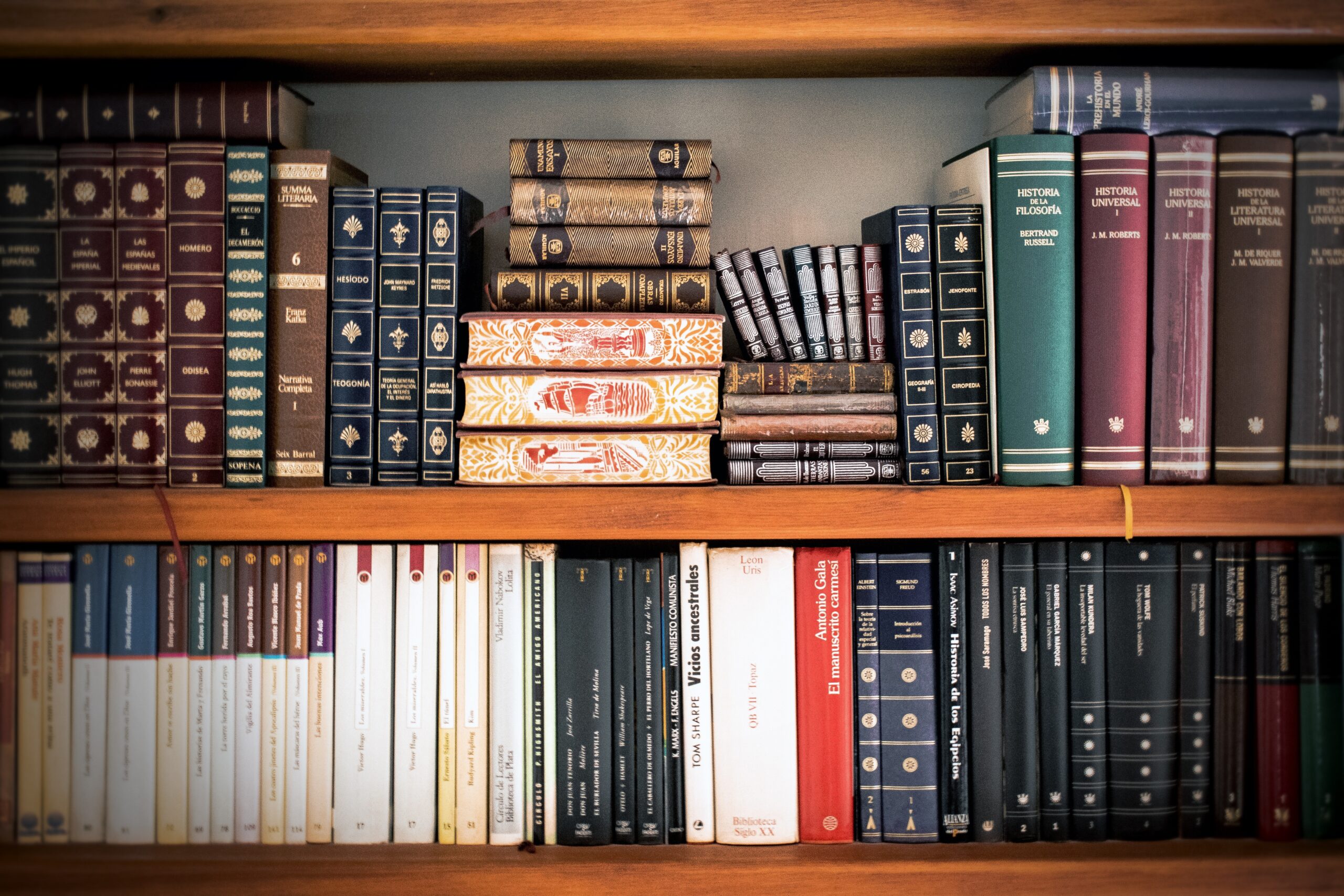 Books on a tidy shelf in what looks like an office.